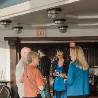 President Mantella talks to older couple and women while holding glasses